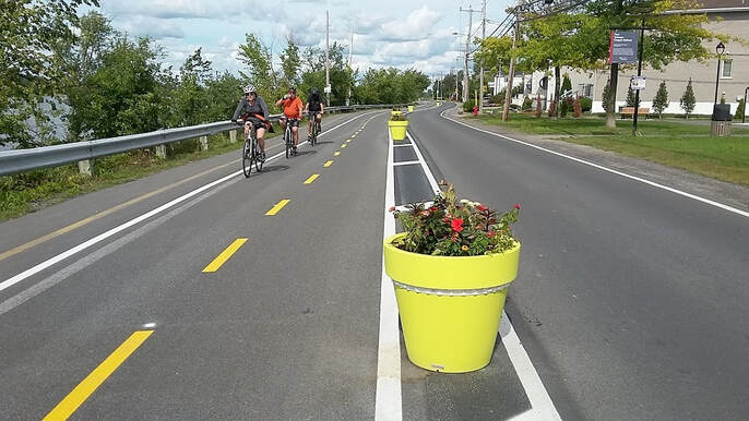 Piste cyclable le bord de la rivière des Prairies. Pots de fleur entre vélos et voitures.