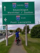 Moi à vélo passant en-dessous d'un grand panneau à Trois-Rivières