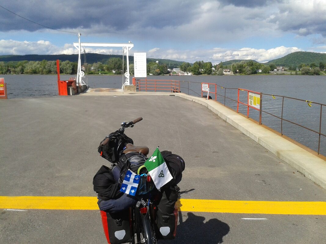 Vélo chargé avec drapeau franco-ontarien et celui du Québec, sur un traversier